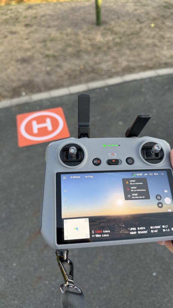 Fernsteuerung der Drohne. DJI mini 4 Pro und Landmatte im Hintergrund